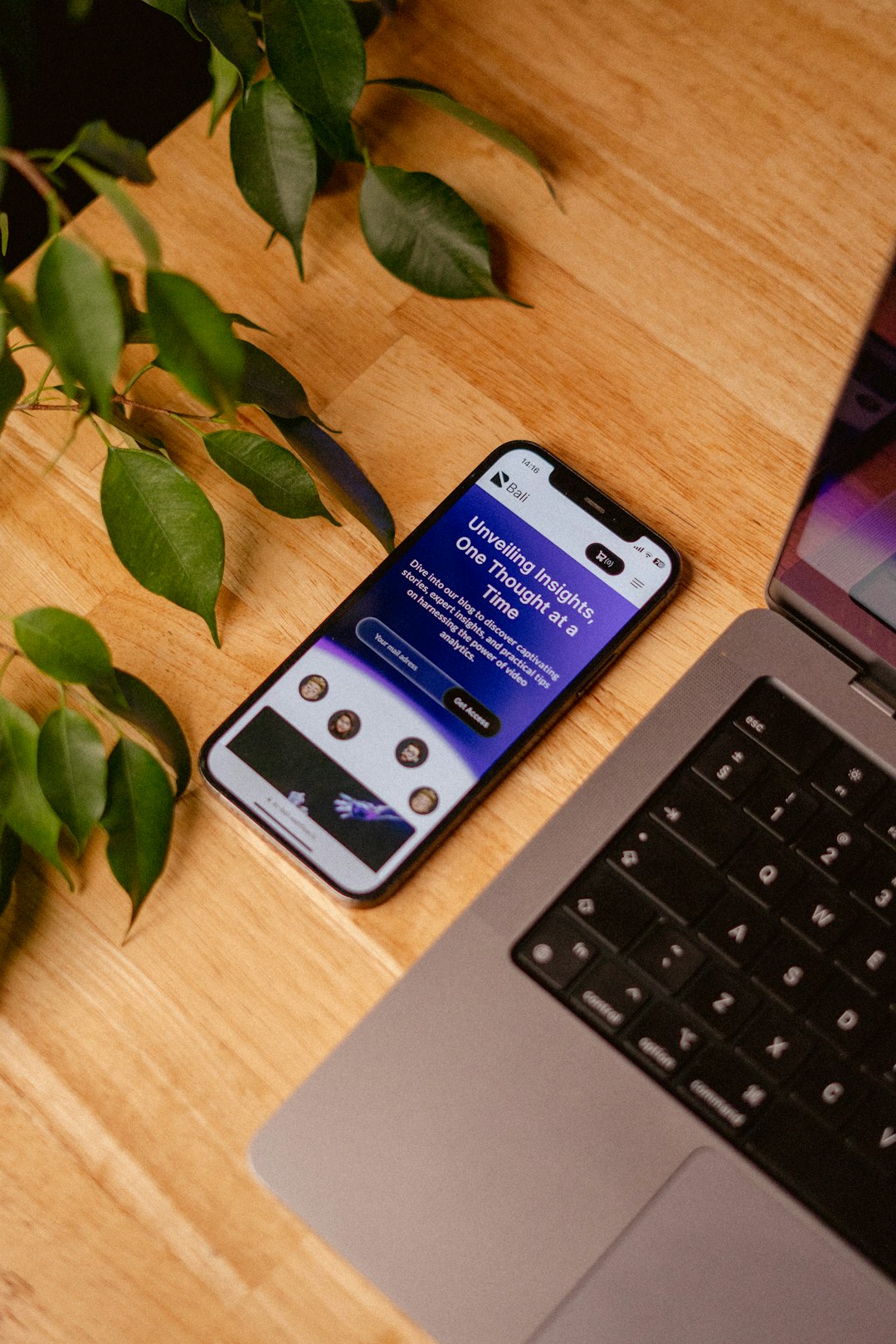 a-cell-phone-sitting-on-top-of-a-wooden-table-next-to-a-laptop-usx99gjosoc